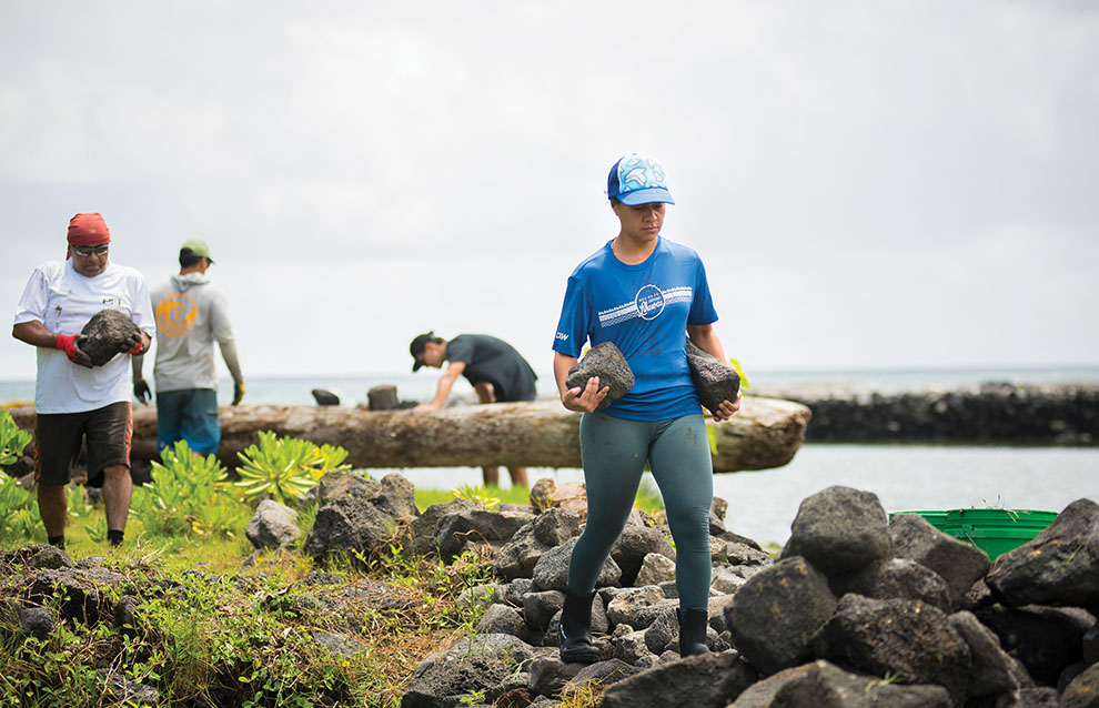 a person carrying rocks by a body of water