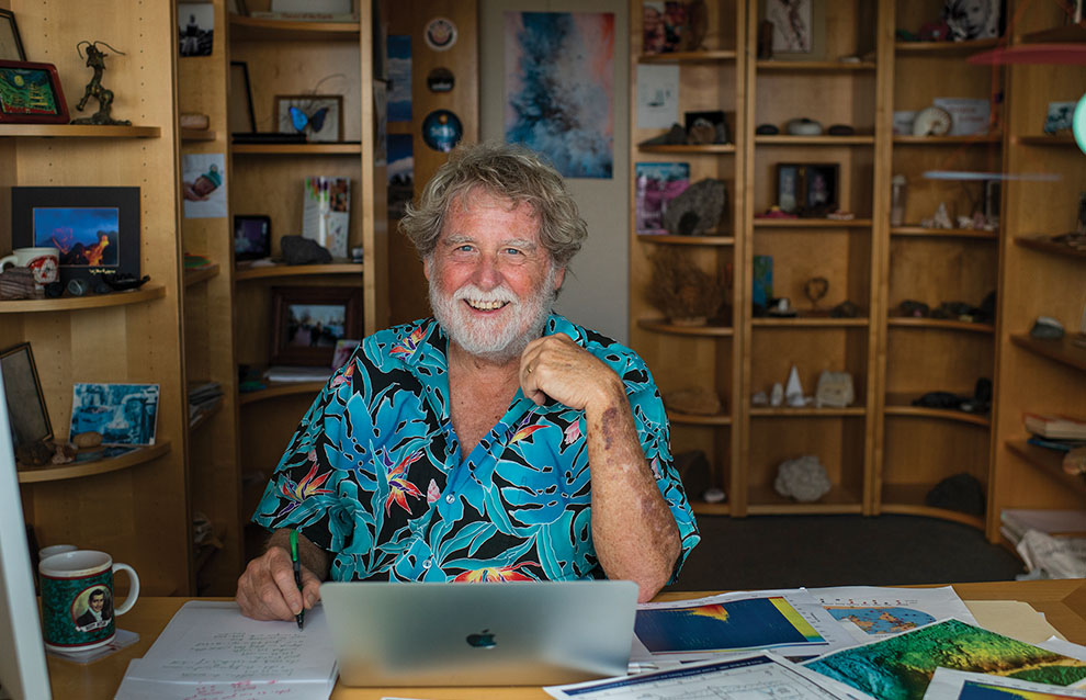 a person sitting at a desk with a laptop and a pen