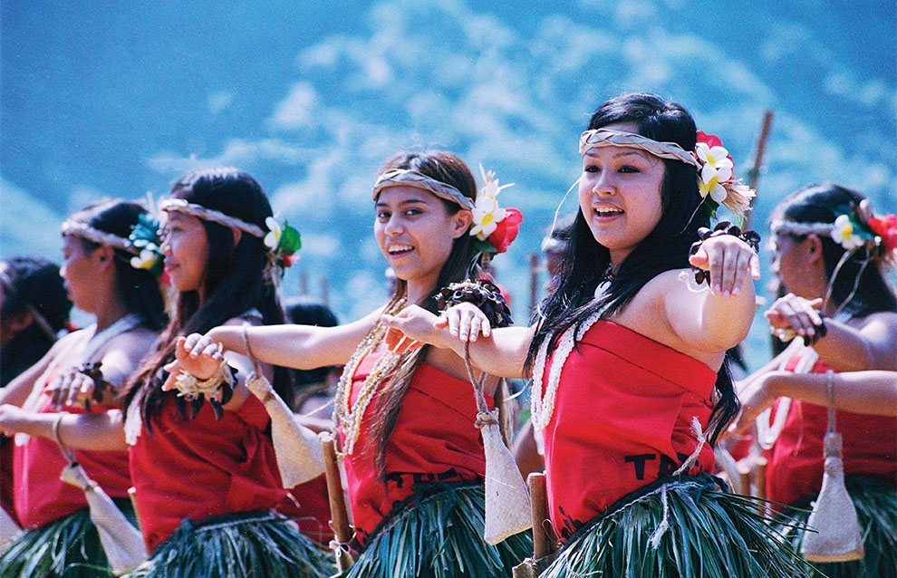 a group of women dancing in grass skirts