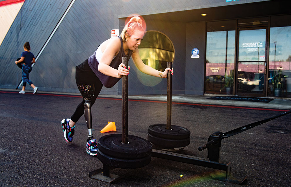 strong woman with prosthetic leg pushes weights at the gym.