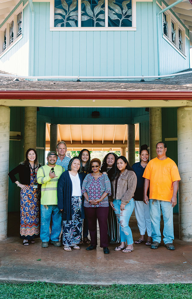 ten community members group together smiling under an archway.