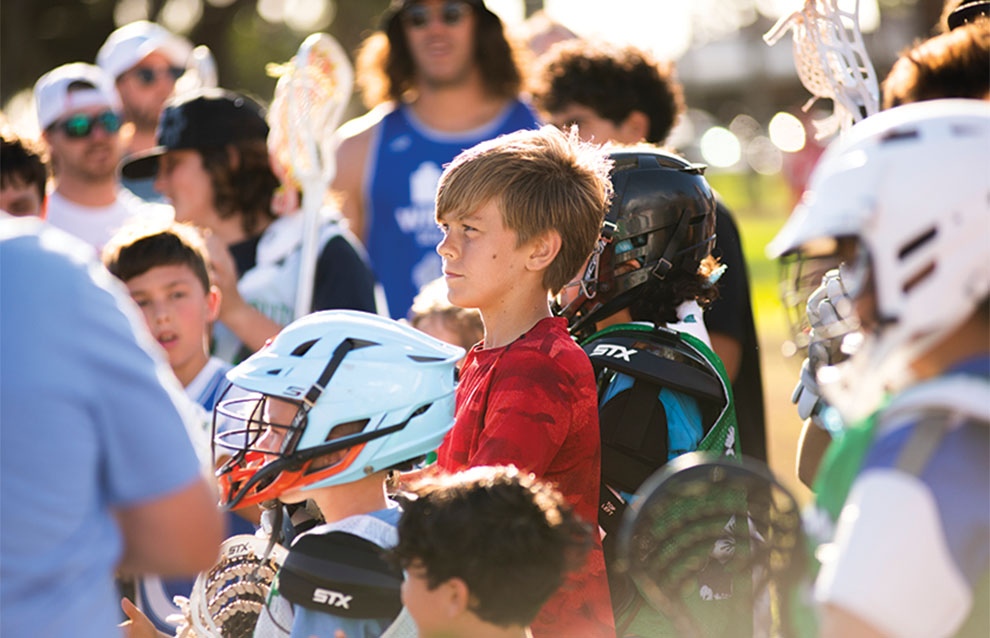 boy in crowd watching the lacrosse game intently.