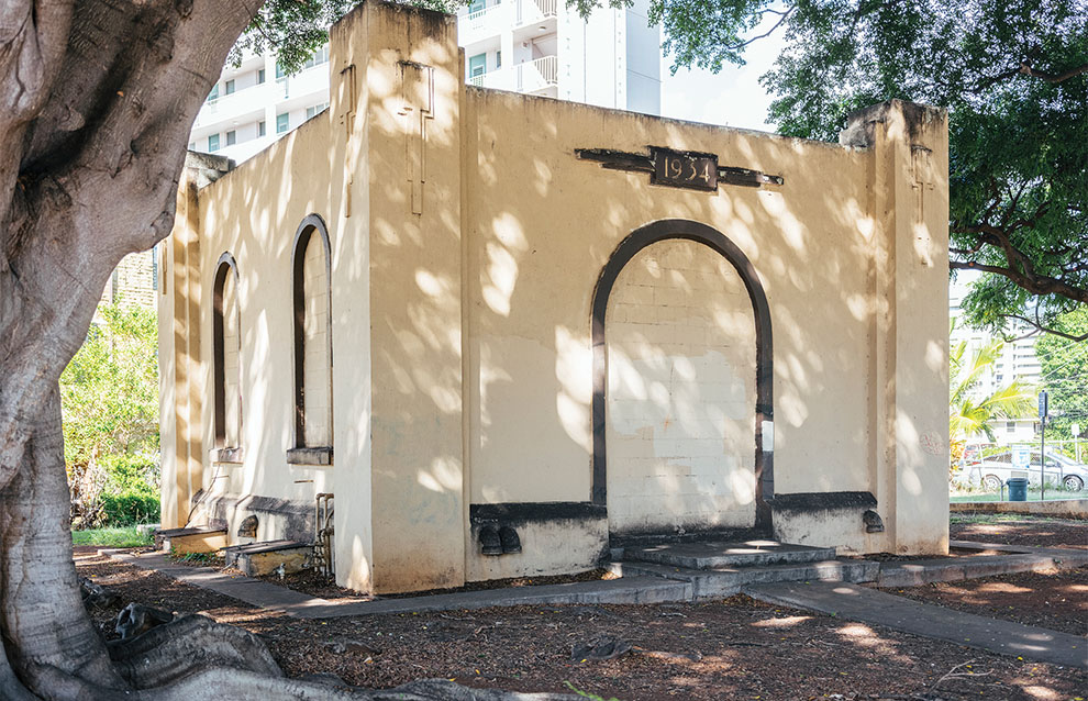 small, beige building in a park.