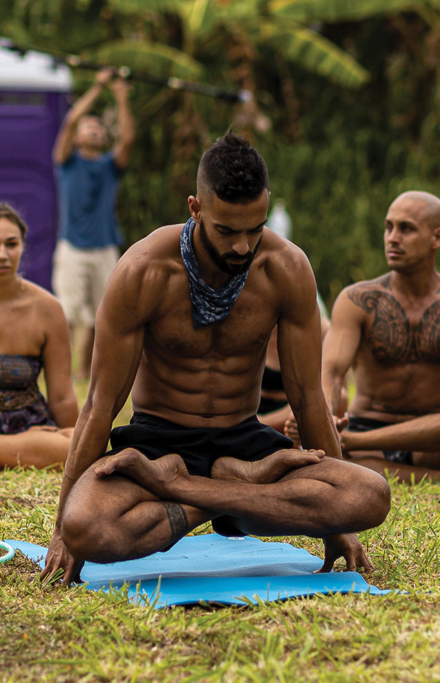 man sits crossed legged hovering above yoga mat.