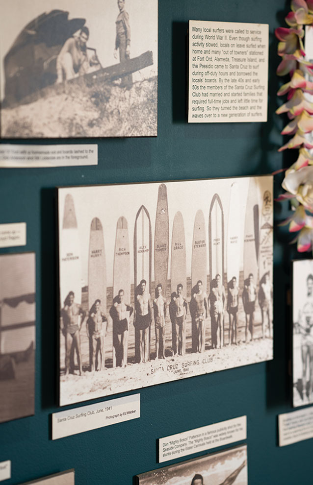 a group of men standing in a line of surfboards on a wall