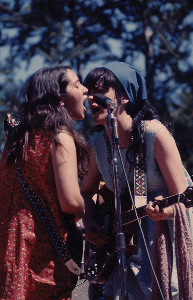 a person singing into microphones with a guitar and a person with a guitar